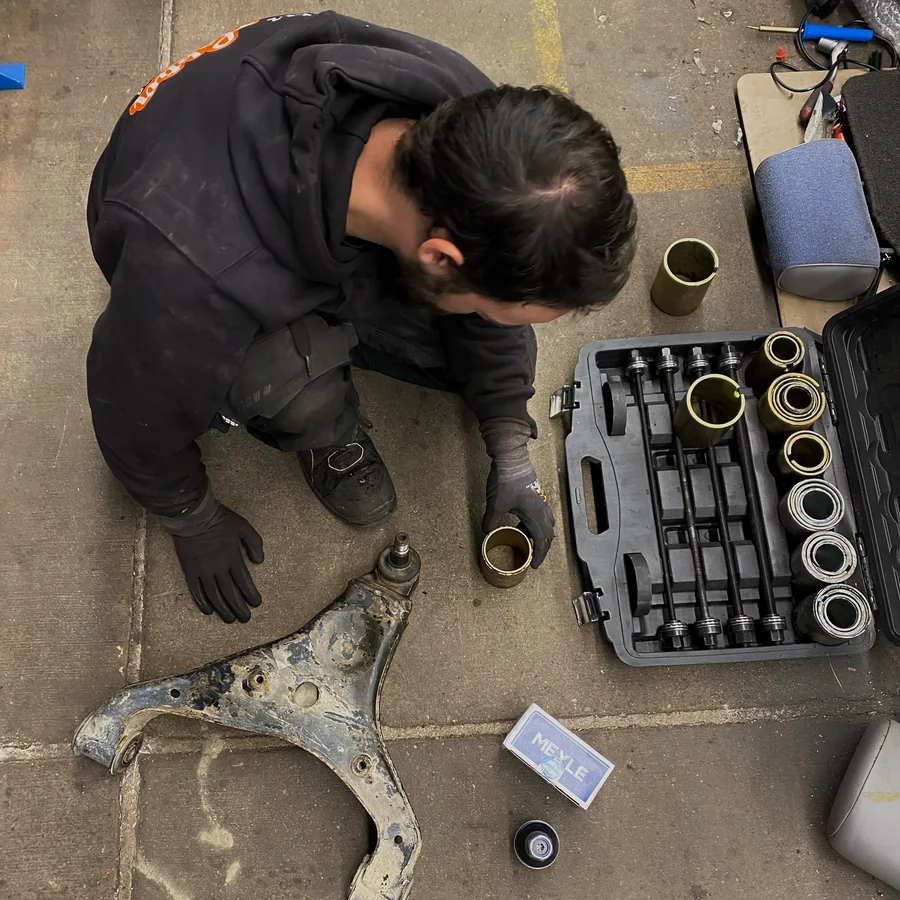 Ausgebauter Querlenker und sortiertes Werkzeug in der Werkstatt